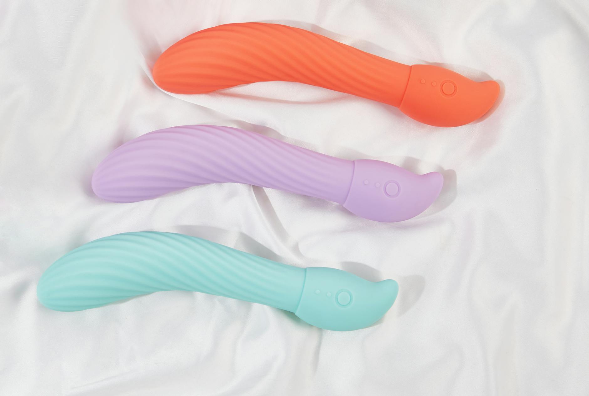 Woman holding colorful clitoral vibrators in a contemplative pose