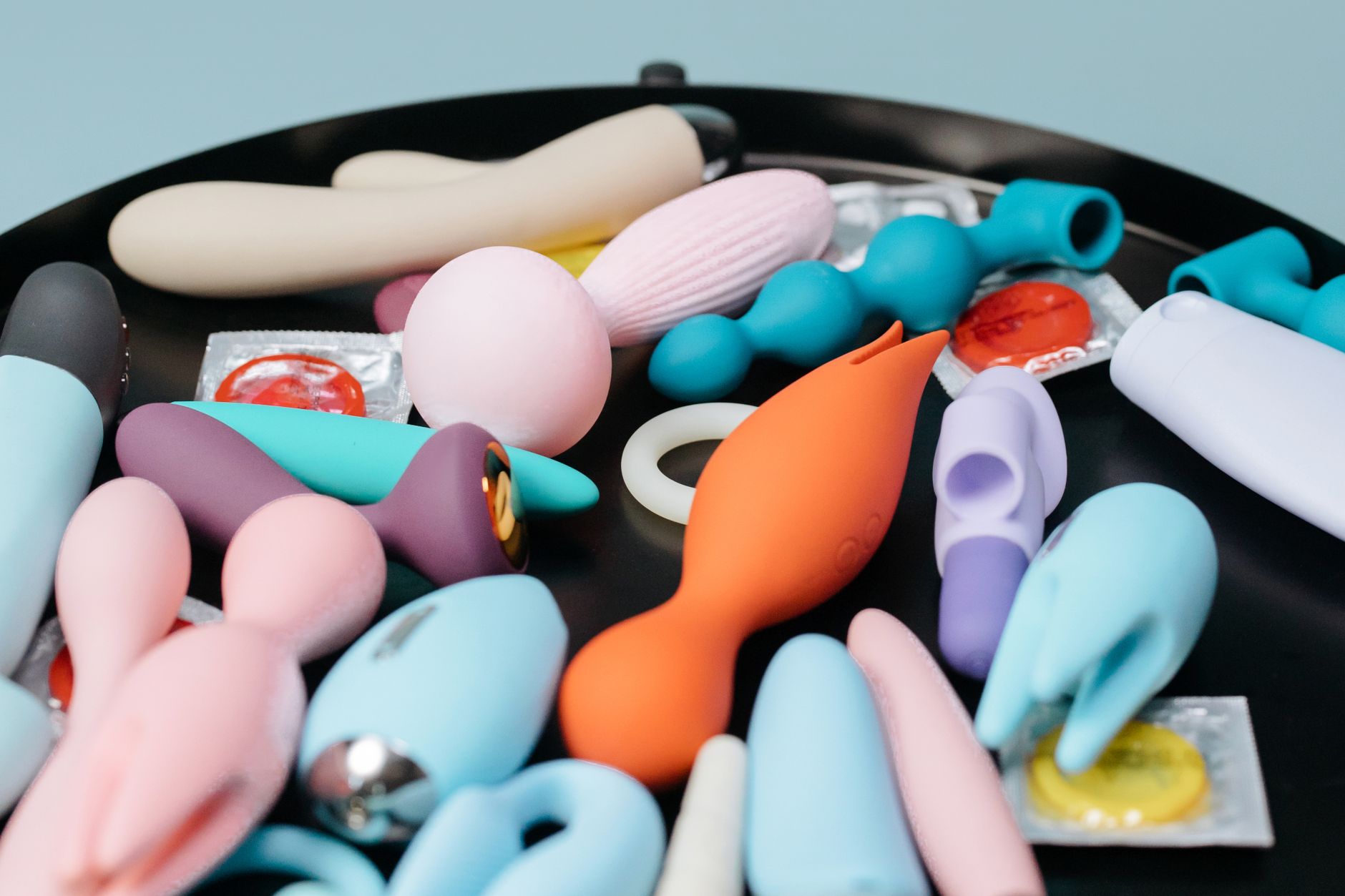 Collection vibrante de jouets pour adultes sur un plateau noir, présentant des formes et des couleurs variées