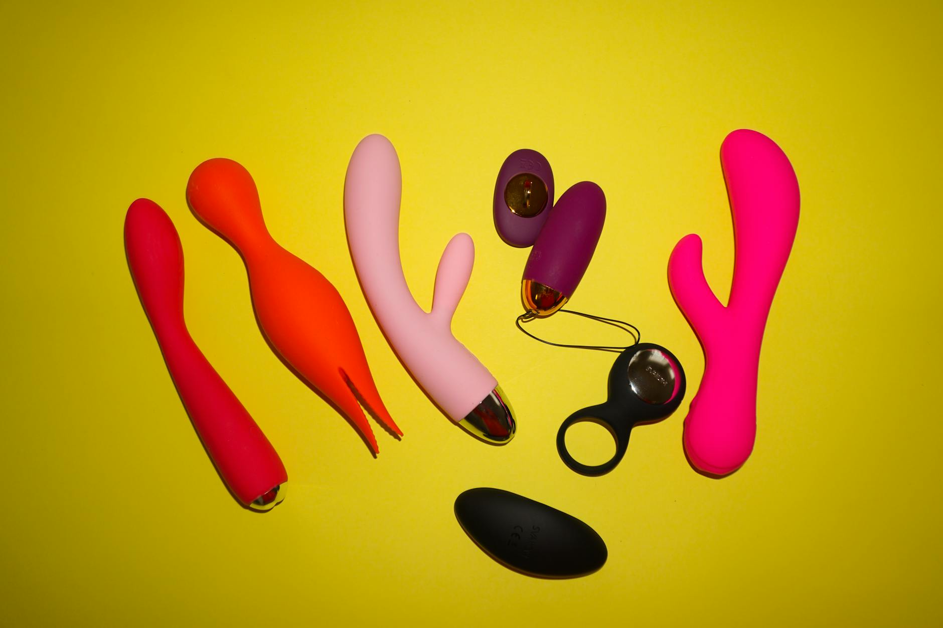 A hand holding an orange vibrator against a minimalistic purple backdrop